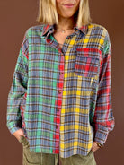 Model wearing the ROYally Cute oversized button-front flannel with green, blue, yellow, and red mixed plaid panels, paired with olive pants.
