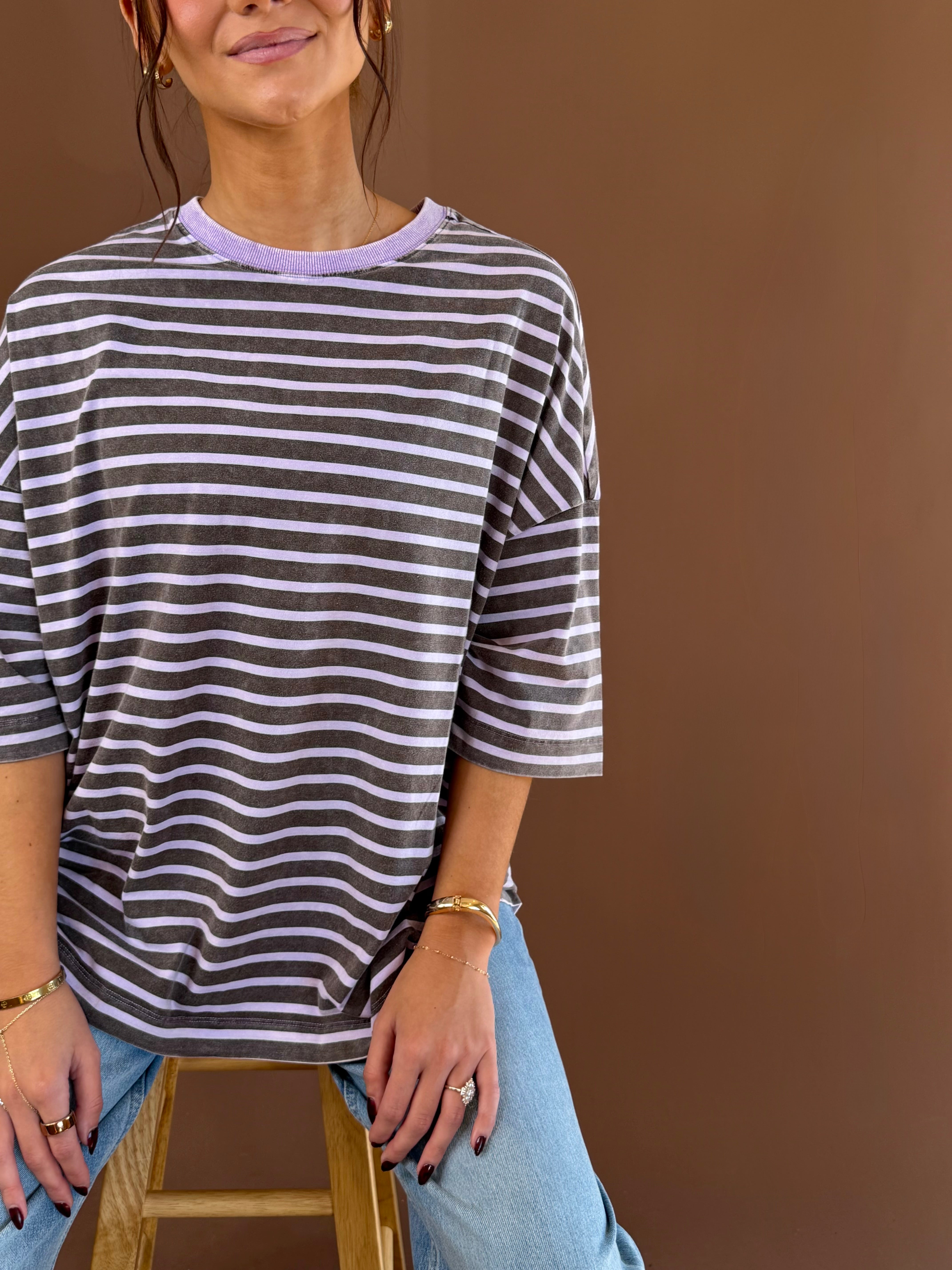 Model wearing a purple and white striped cotton tee with short sleeves and a round neckline, styled with jeans.