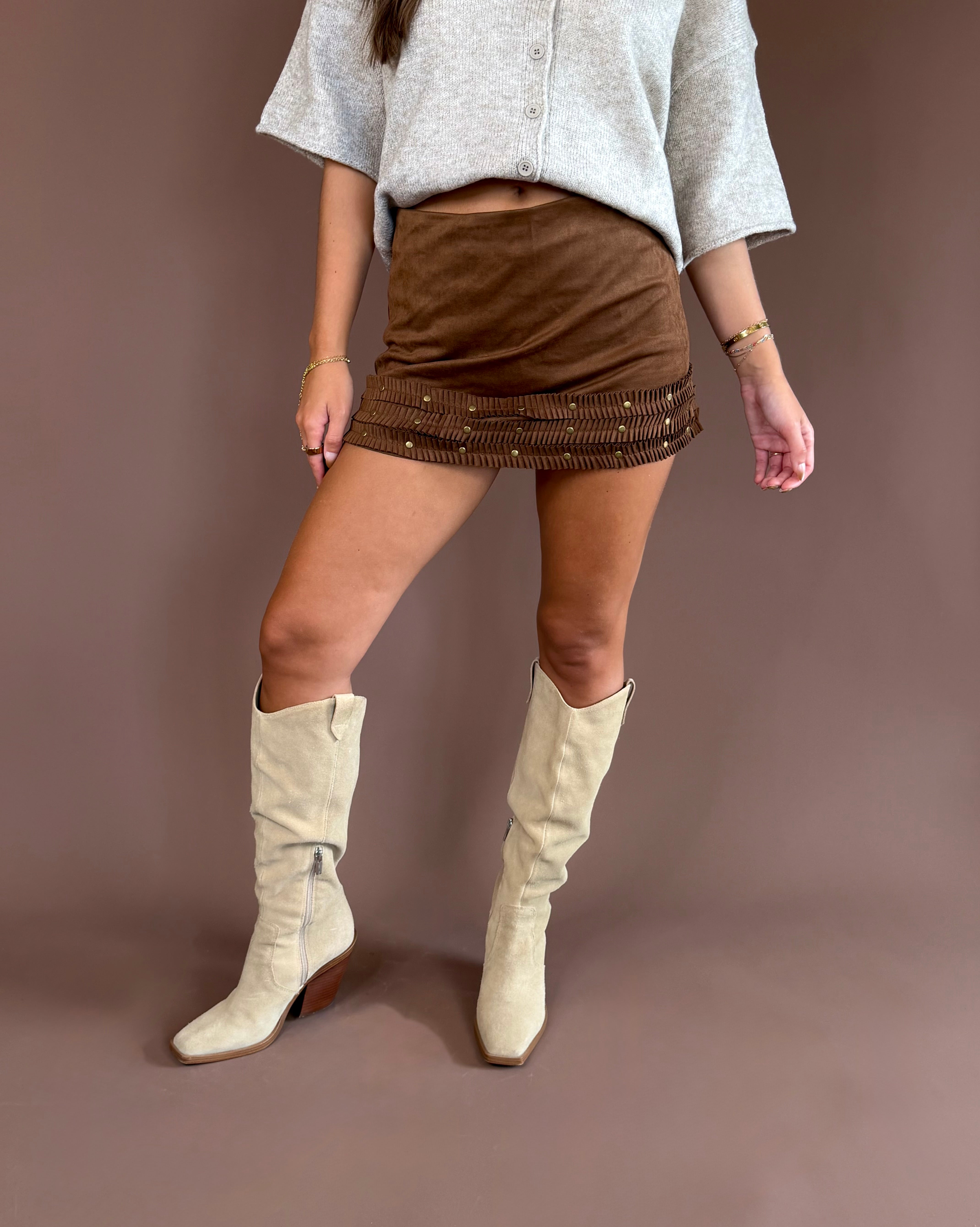 Wild West Darling women’s brown suede mini skirt with three ruffle tiers, studded western details, and built-in shorts.