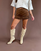 Wild West Darling women’s brown suede mini skirt with three ruffle tiers, studded western details, and built-in shorts.