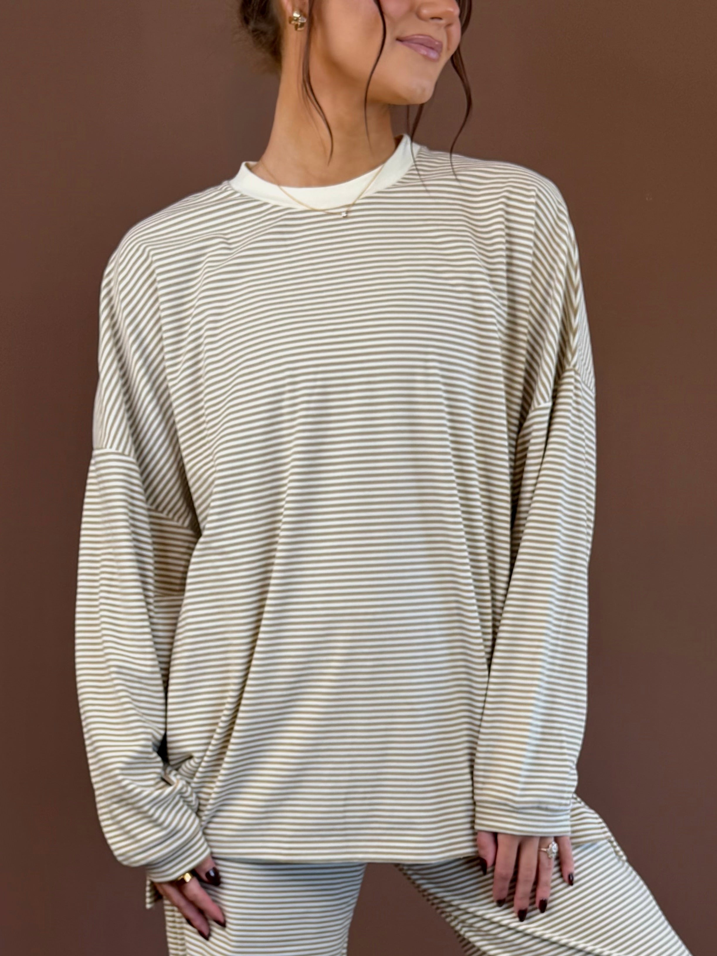 Model wearing an oversized beige and tan striped long sleeve top with white neckline trim and matching lounge pants.