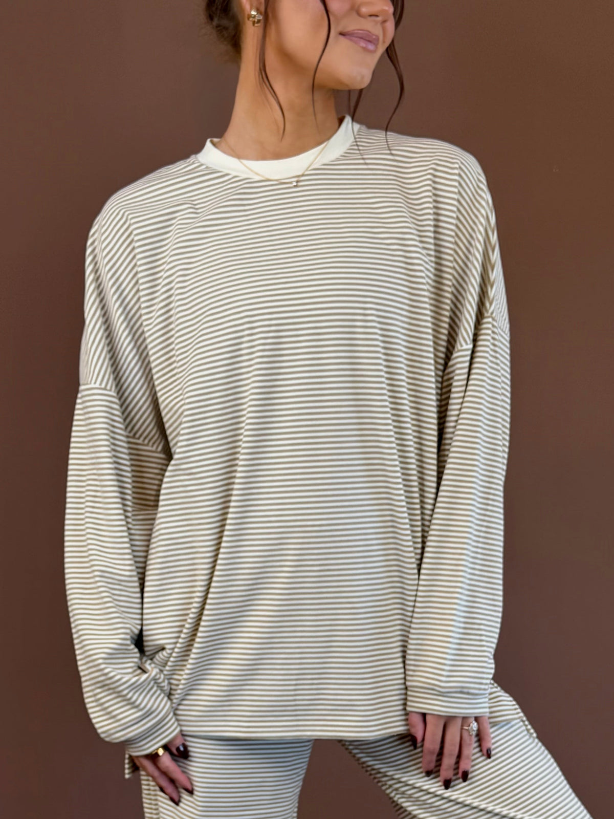 Model wearing an oversized beige and tan striped long sleeve top with white neckline trim and matching lounge pants.