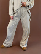 Model wearing beige and tan striped wide leg lounge pants with a matching long sleeve top and brown clogs.