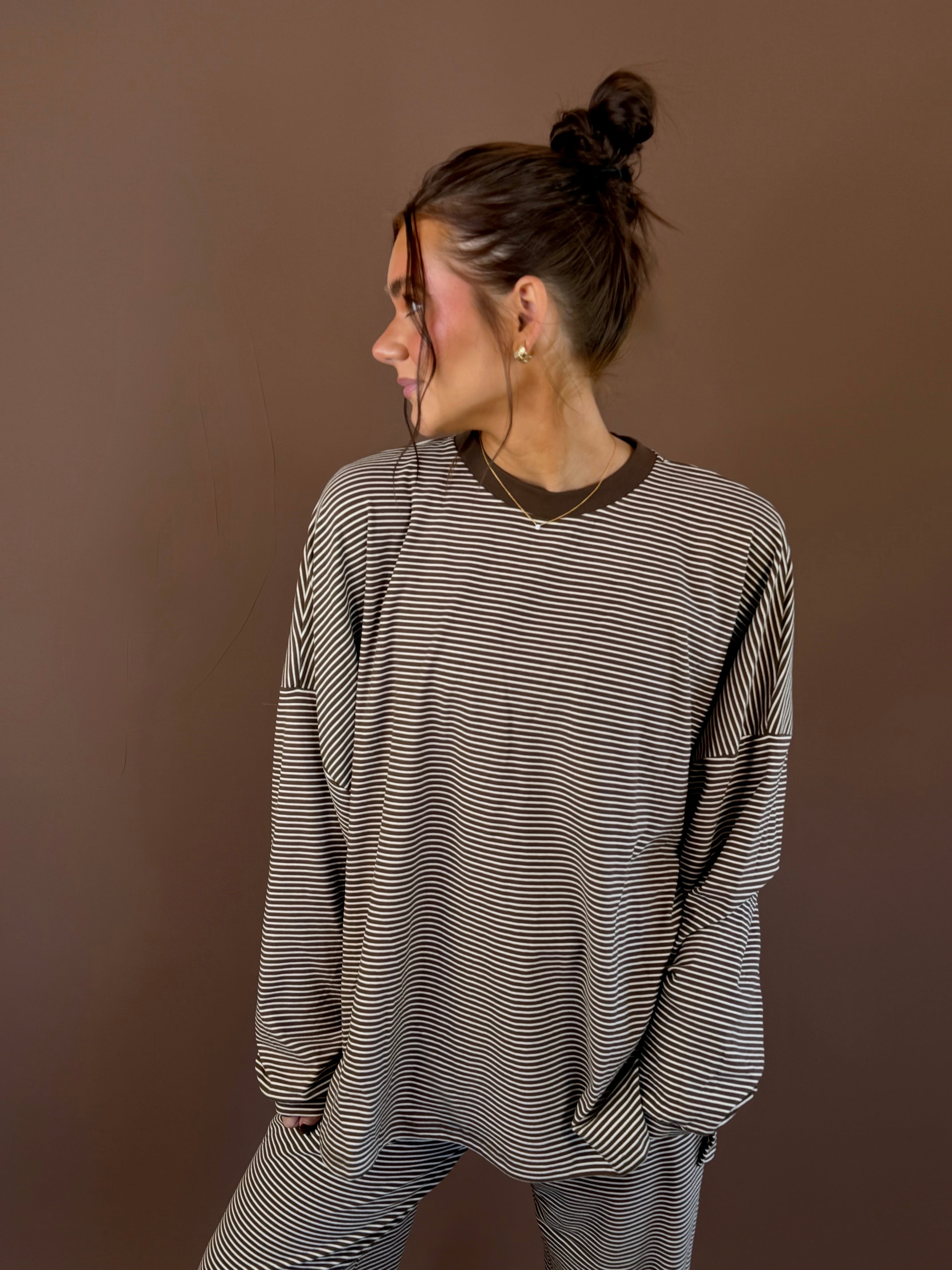 Model wearing an oversized cocoa striped long sleeve lounge top with a round neckline and matching pants.
