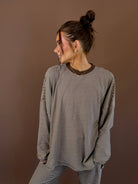 Model wearing an oversized cocoa striped long sleeve lounge top with a round neckline and matching pants.
