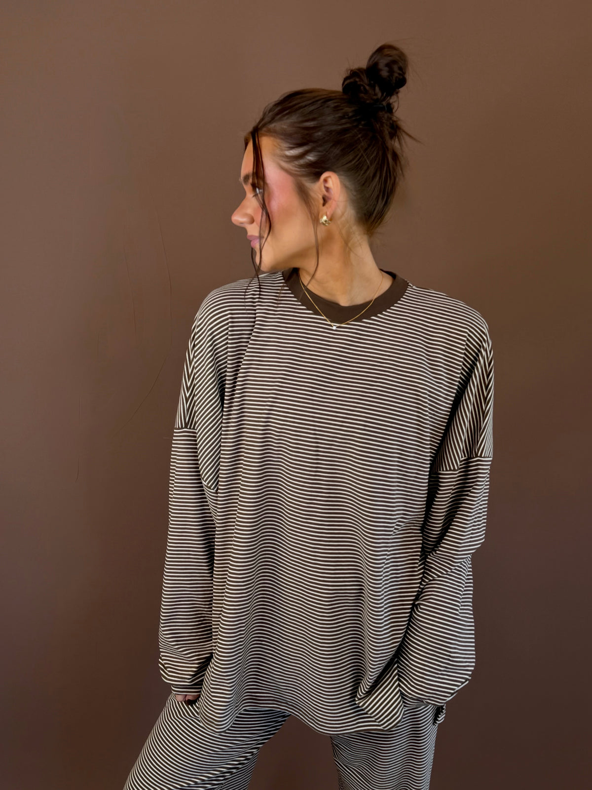 Model wearing an oversized cocoa striped long sleeve lounge top with a round neckline and matching pants.