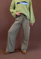 Model wearing green and cream striped wide leg lounge pants with an olive sardine sweater and brown clogs.