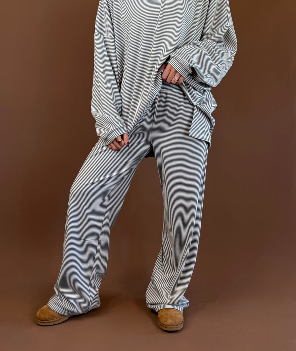 Model wearing gray striped wide leg lounge pants with an elastic waist, styled with the matching long sleeve top and clogs.